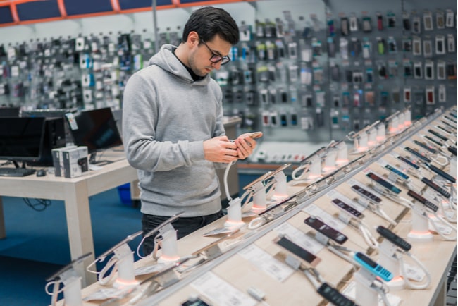 Man tittar på telefoner i elektronikaffär